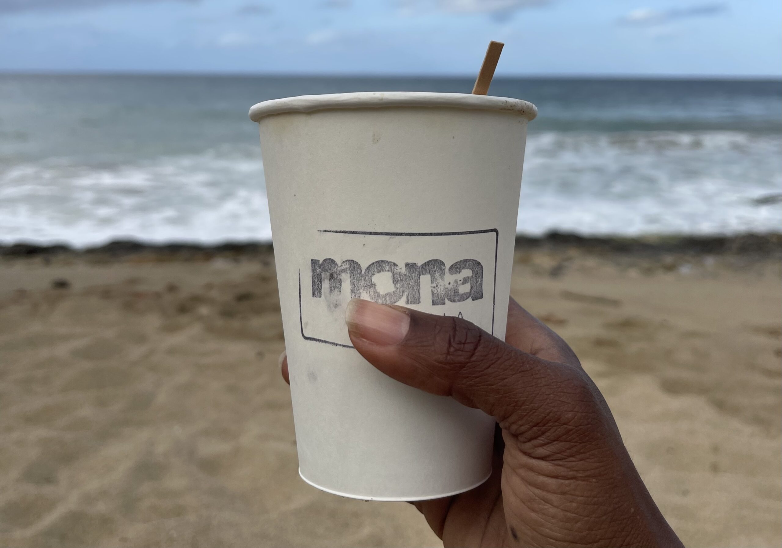 Allison Tibbs is holding a coffee cup on a beach in puerto rico.
